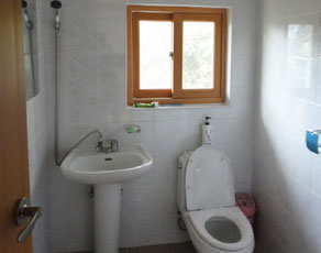 욕실의 모습으로 변기와,세면대 그리고 샤워호스가 벽에 걸려있는 모습