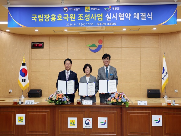 국가보훈부 전라남도 장흥군  국립장흥호국원 조성사업 실시협약 체결식 2024.6.19(수) 15:30 장흥군청 대회의실 현수막 아래에서 협약서를 들고 사진을 찍는 관계자들