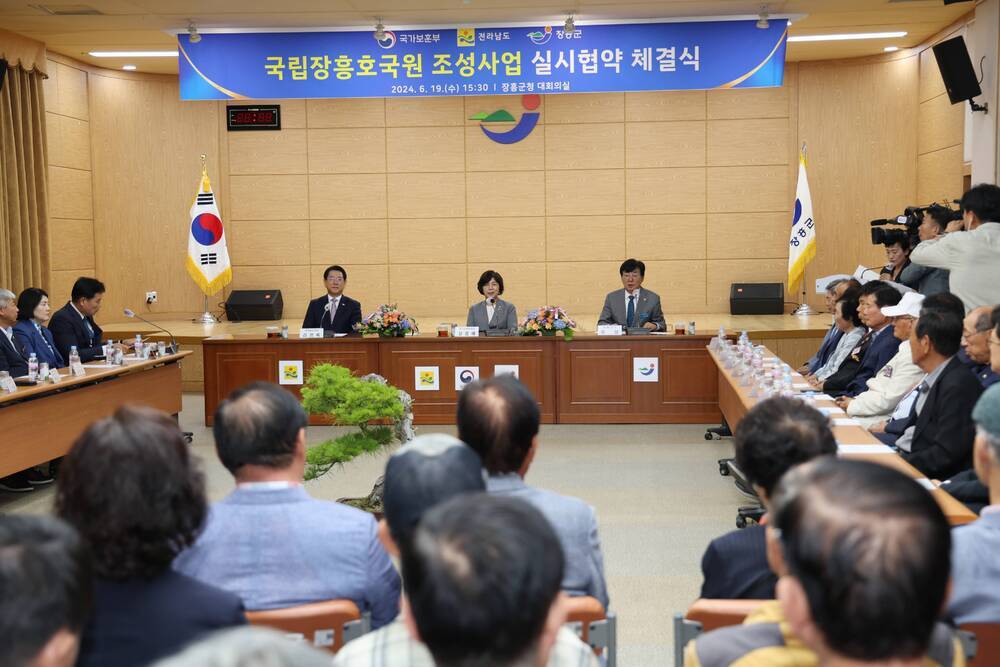 국립장흥호국원 조성사업 실시협약 체결식 현수막을 걸고 협약식을 가지고있는 관계자들